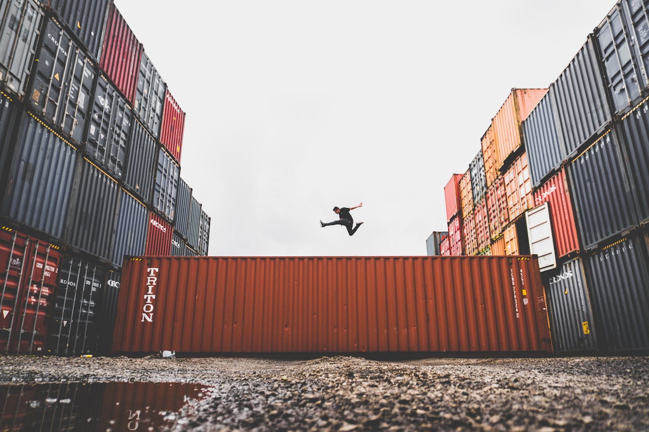 A man jumping above a red shipping container.