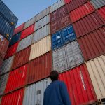 Man Looking Up at Shipping Containers