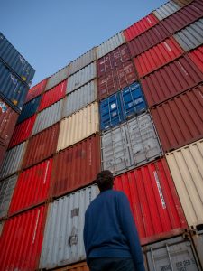 Man Looking Up at Shipping Containers