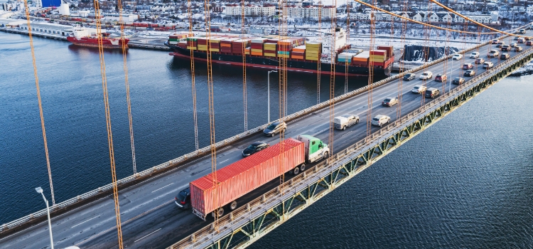 A photo of a red-truck and other small cars driving over a cable bridge.