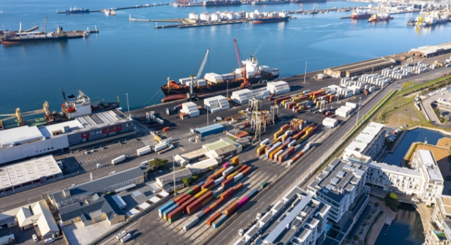 A photo of a shipping port with containers, buildings, and ships.